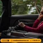 Passenger seated in the back of a luxury Crown Limousine, speaking on the phone, with premium leather seating, bottled water in the console, and company branding visible, trees outside the window.