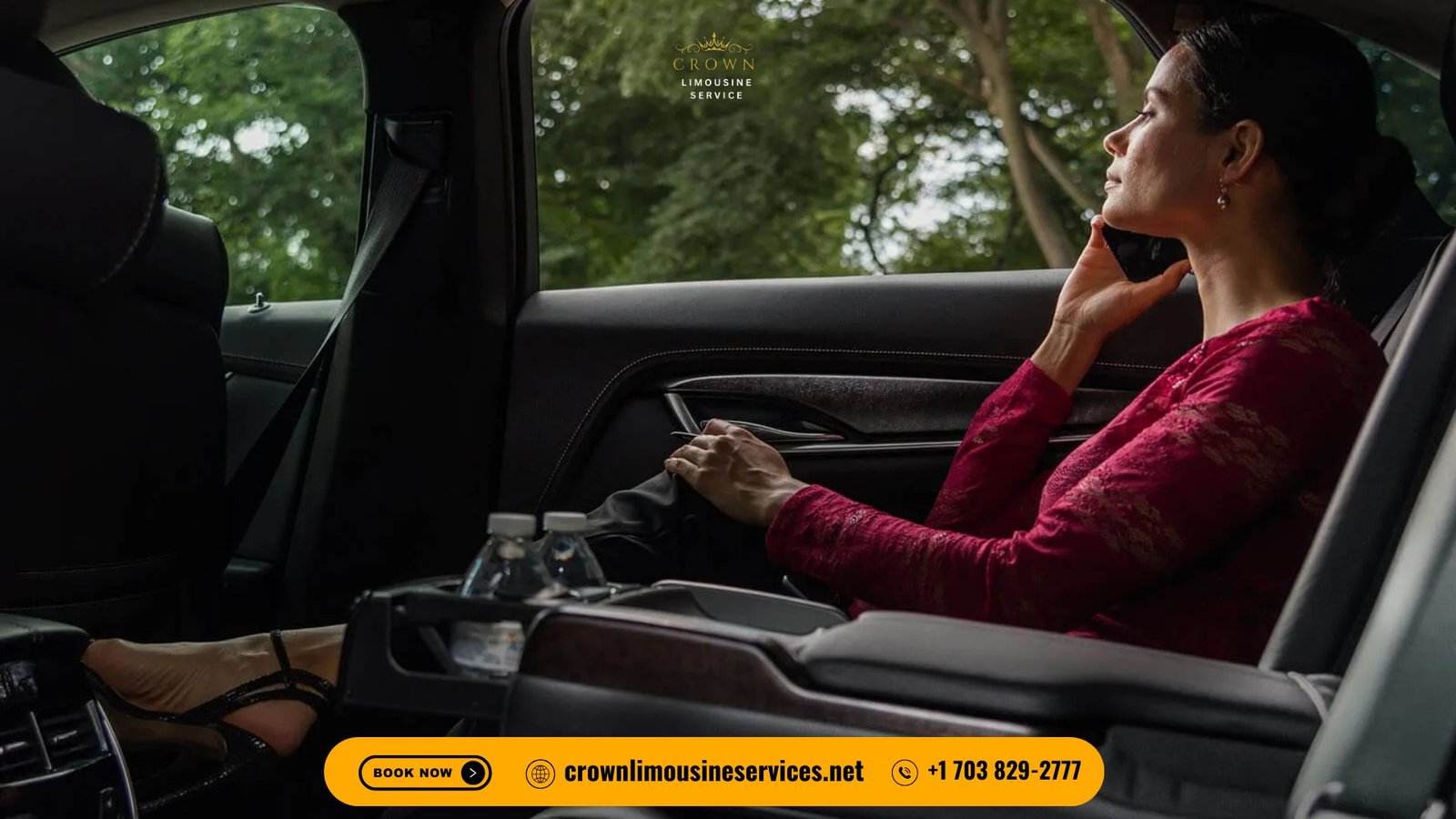 Passenger seated in the back of a luxury Crown Limousine, speaking on the phone, with premium leather seating, bottled water in the console, and company branding visible, trees outside the window.