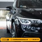 A sleek black luxury sedan parked in front of an upscale hotel